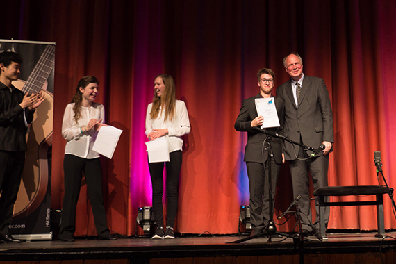 Prof. Martin Maria Krüger, der Präsident des Deutschen Musikrates überreicht Georgi Dimitrov seinen 1. Preis der AG II. Im Hintergrund Ronja Schubert (Deutschland) Lucia Stivević (Kroatien) und Jeseok Bang (Korea) 