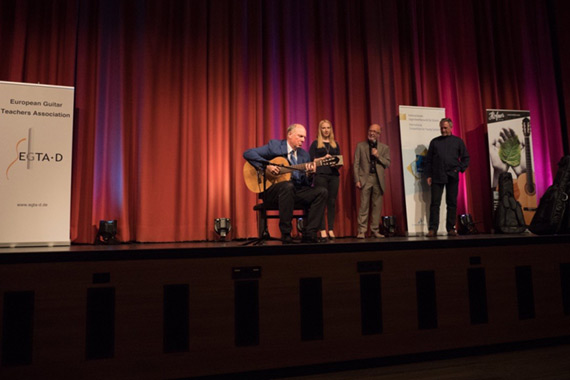 Der Präsident des deutschen Musikrates, Prof. Martin Maria Krüger, testet spontan eine gestiftete
Höfner Gitarre. Im Hintergrund Heinz-Jürgen Küpper (Chef Organisator und Moderator des Preisträgerkonzertes) und Friedemann Pods (Repräsentant der Firma Höfner)